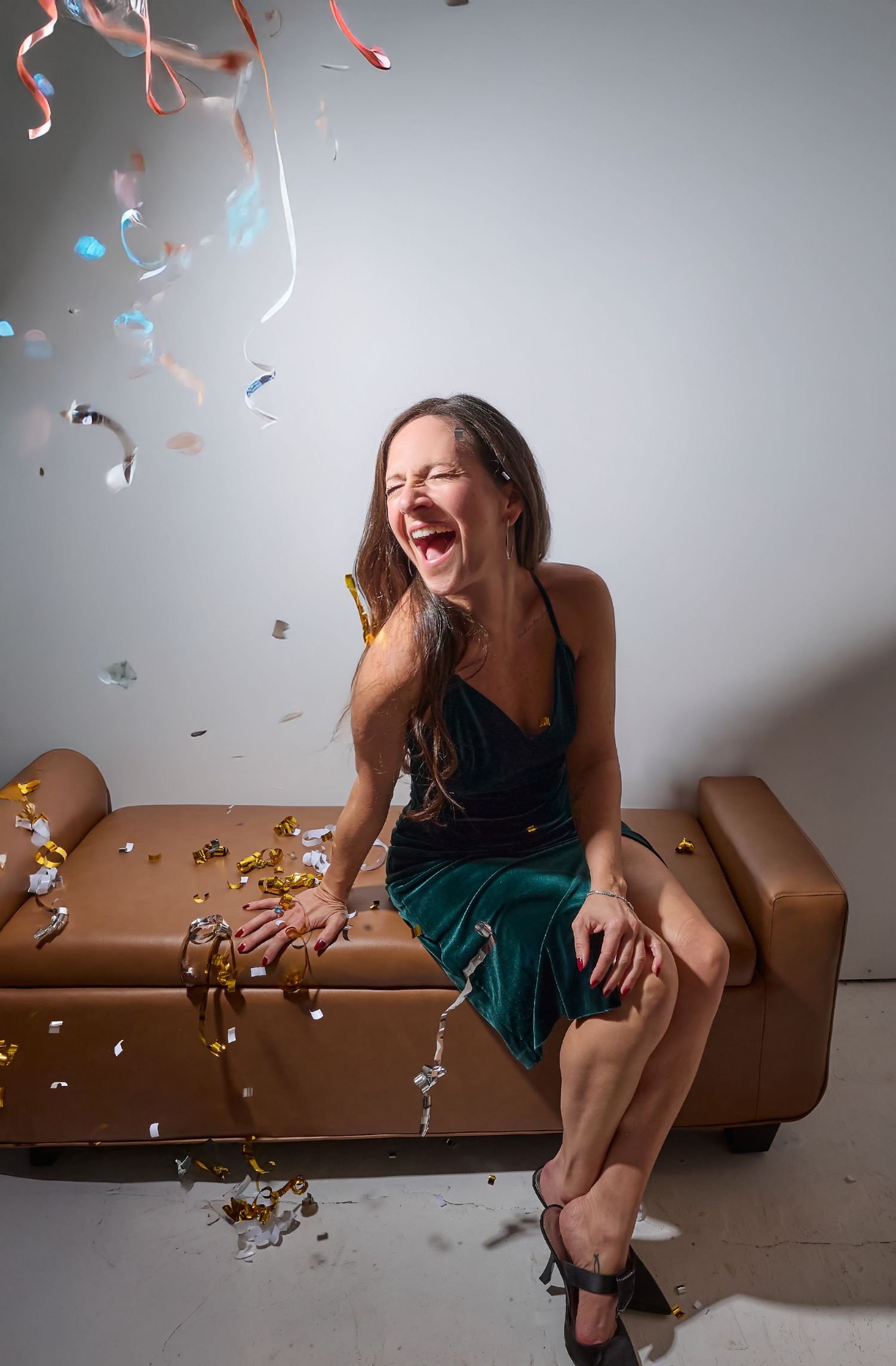 A series of four photos showing someone in a green dress sitting on a brown couch with confetti falling and joyful laughter.