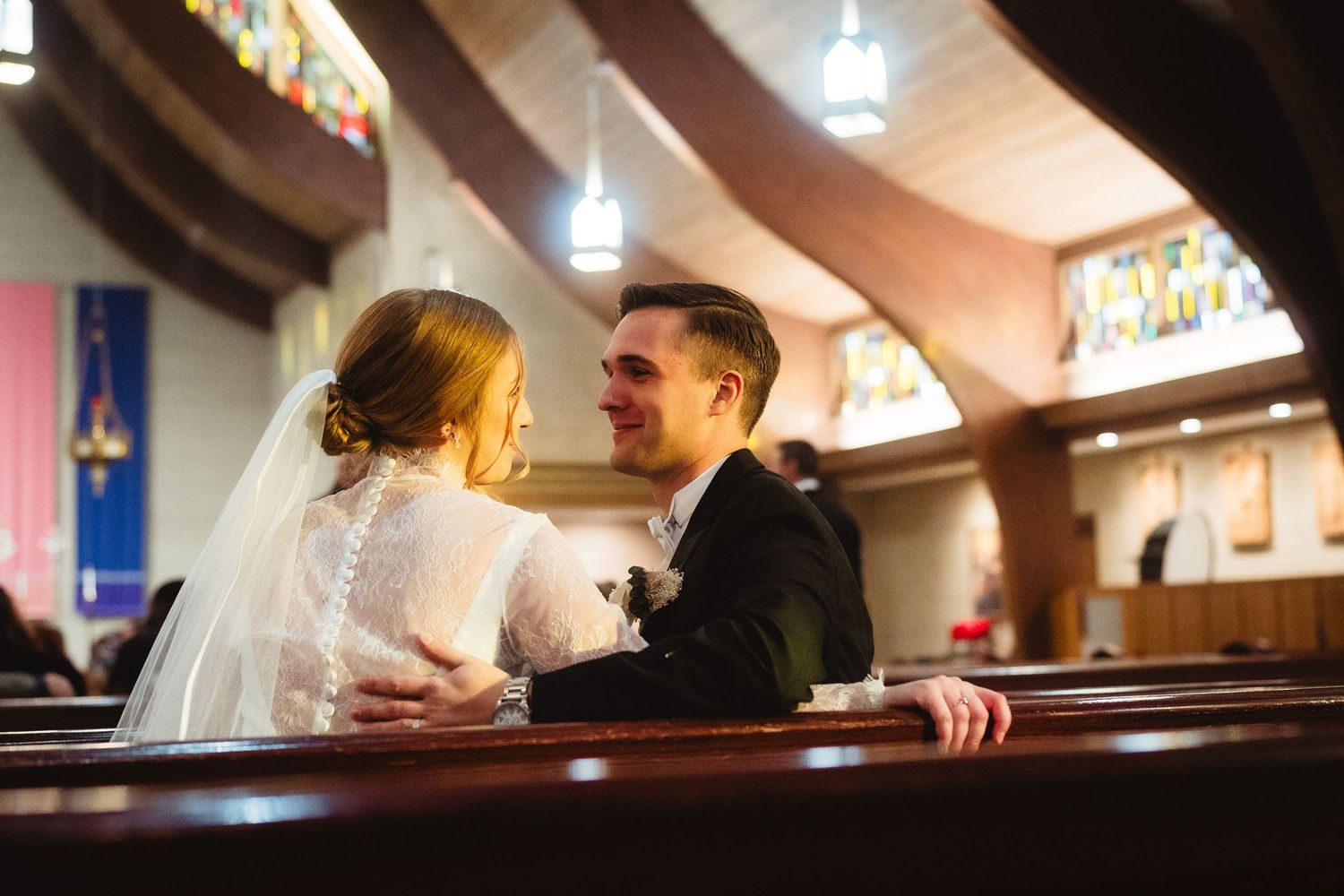 A couple shares an intimate moment during their wedding ceremony in a warmly lit church interior.