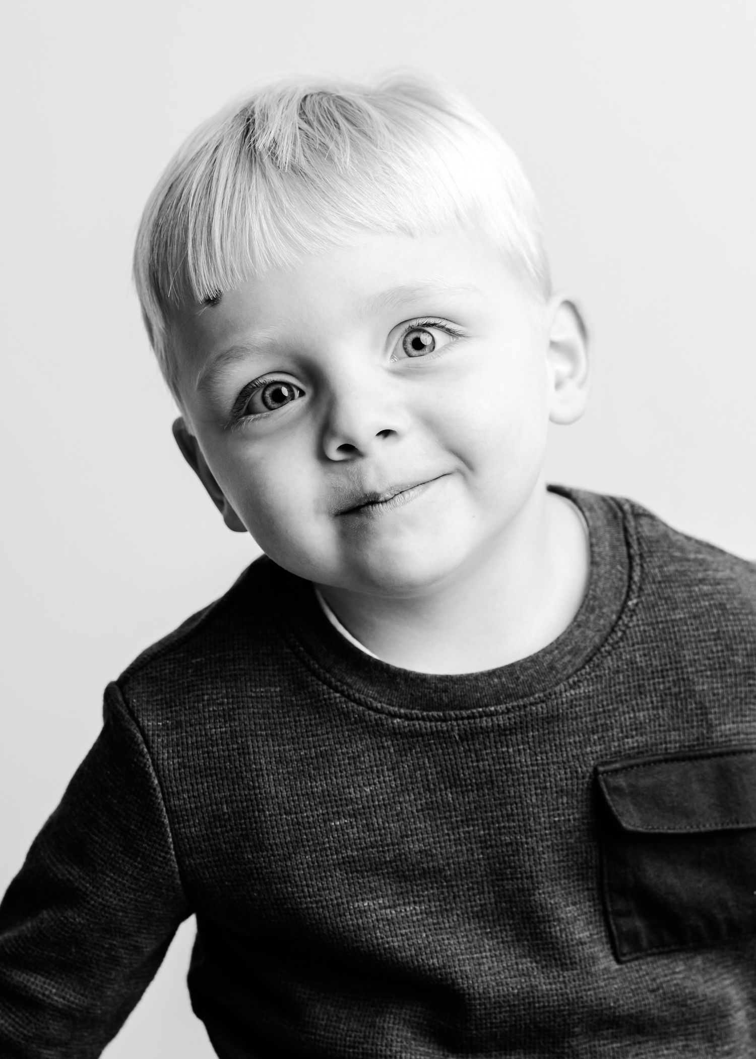 A series of black and white portraits showing playful expressions and movements in a minimalist setting.
