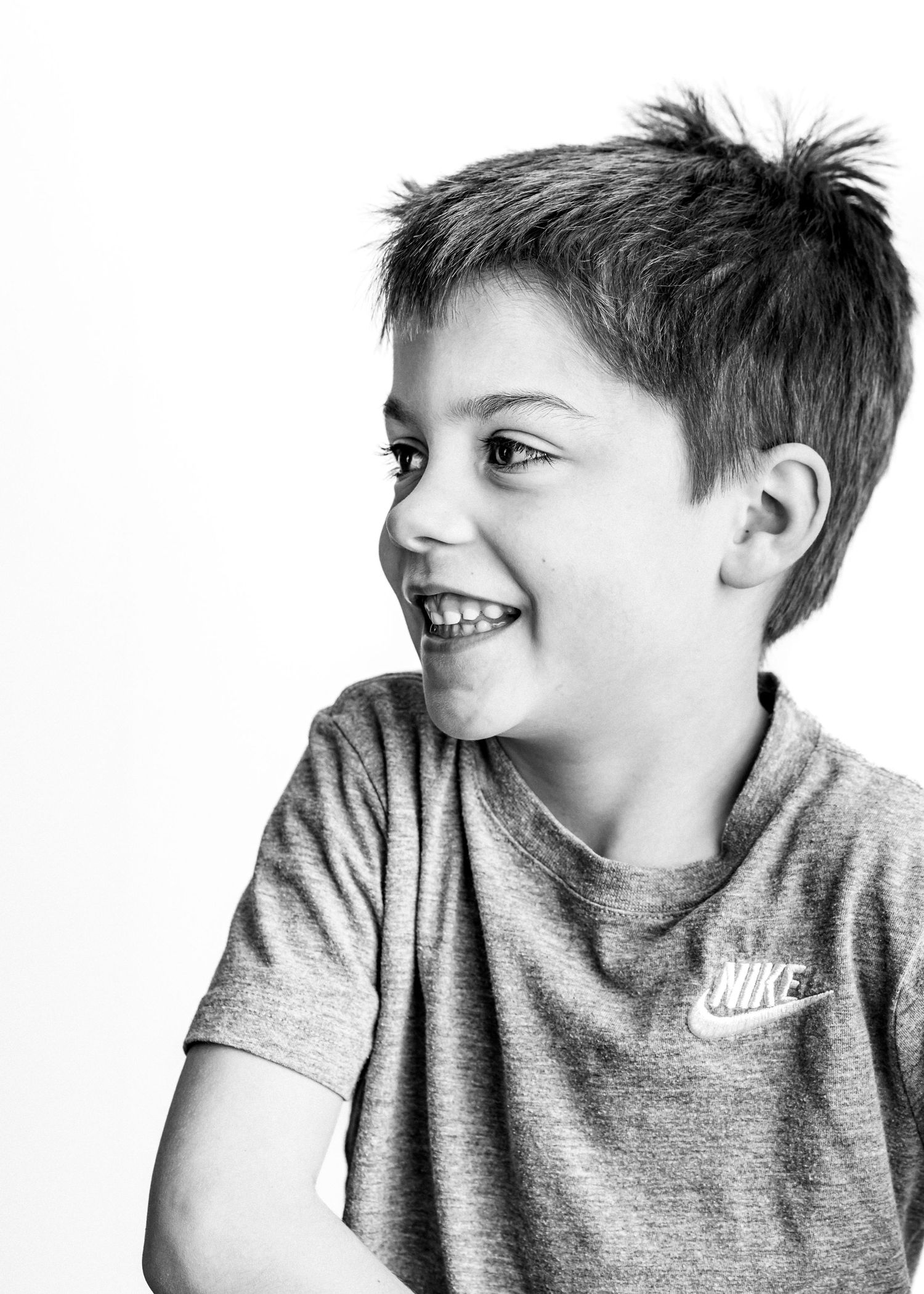 A sequence of four black and white photos showing a child in a Nike shirt making playful expressions.