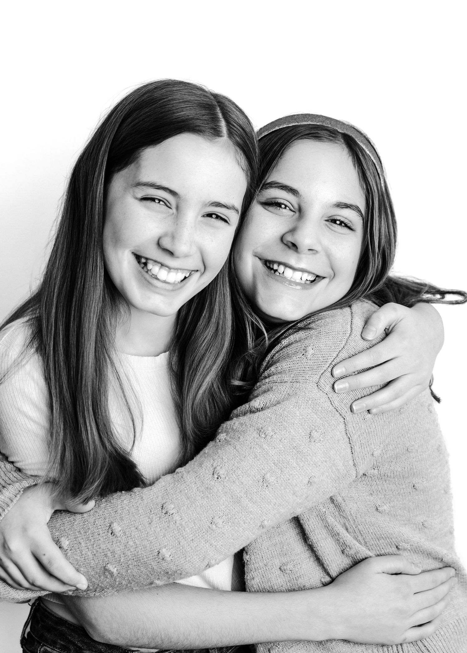 Three people hugging and smiling together in black and white photo with a warm, candid feel.