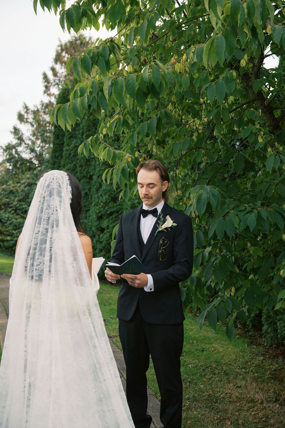 A couple exchanges letters during their first look in a lush garden setting.