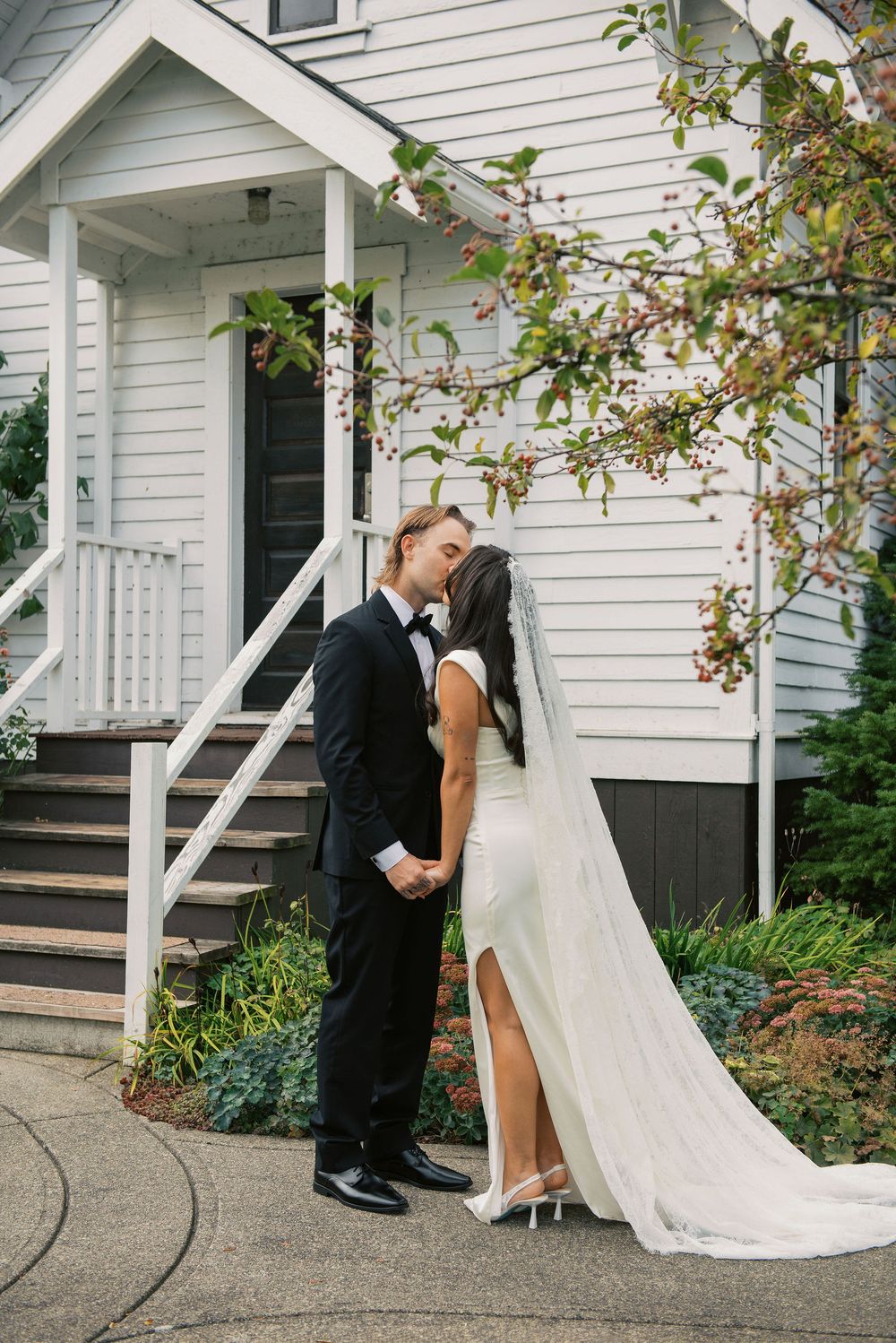 A romantic first look moment between a couple on their wedding day outside a white clapboard house.