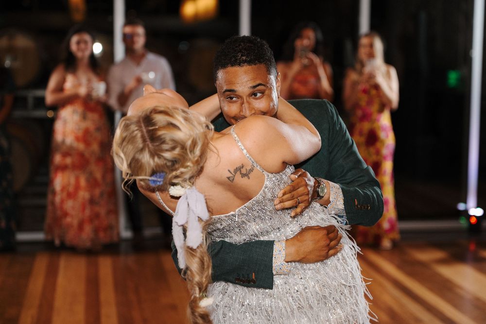 A couple dances together at a wedding reception on a wooden dance floor.
