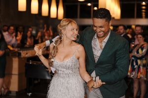 A couple dances together during a wedding reception under warm lighting and surrounded by guests.
