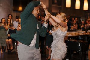 Wedding guests dancing and celebrating on the dance floor during an evening reception with ambient lighting.