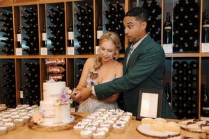 Couple enjoying a wine tasting experience at a winery with extensive bottle displays in the background.