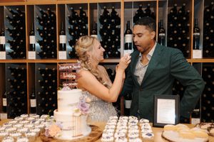 Wine enthusiasts sampling beverages together at a tasting counter with wooden wine racks behind them.