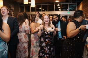 Wedding guests dancing and celebrating on a dimly lit dance floor with hanging pendant lights above.