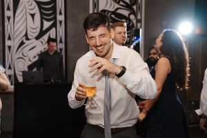 Wedding party members laugh and dance together during an energetic reception celebration.