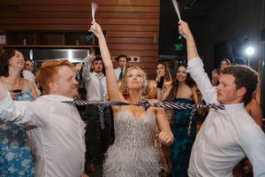 Wedding guests dancing and celebrating together on a dance floor with arms raised in joyful celebration.