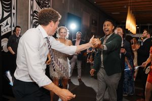 Two people enthusiastically dancing together at a lively party with onlookers in the background.