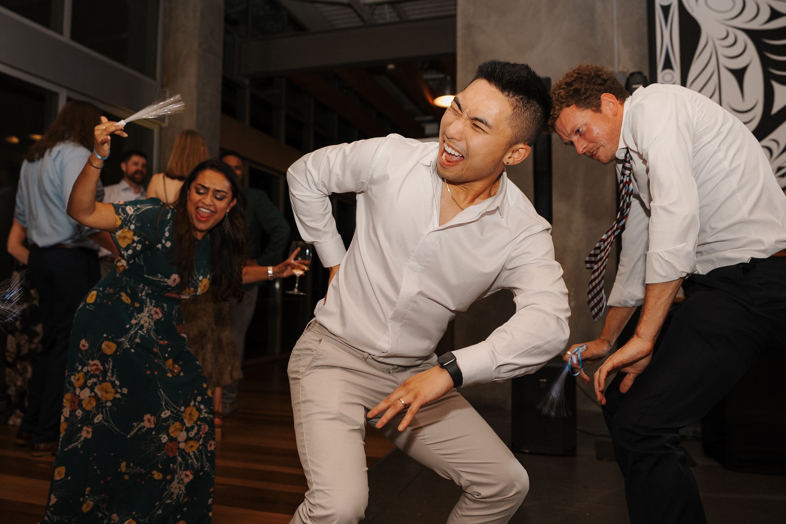 People in white outfits dancing energetically at a party with dark interior lighting and decorative elements.