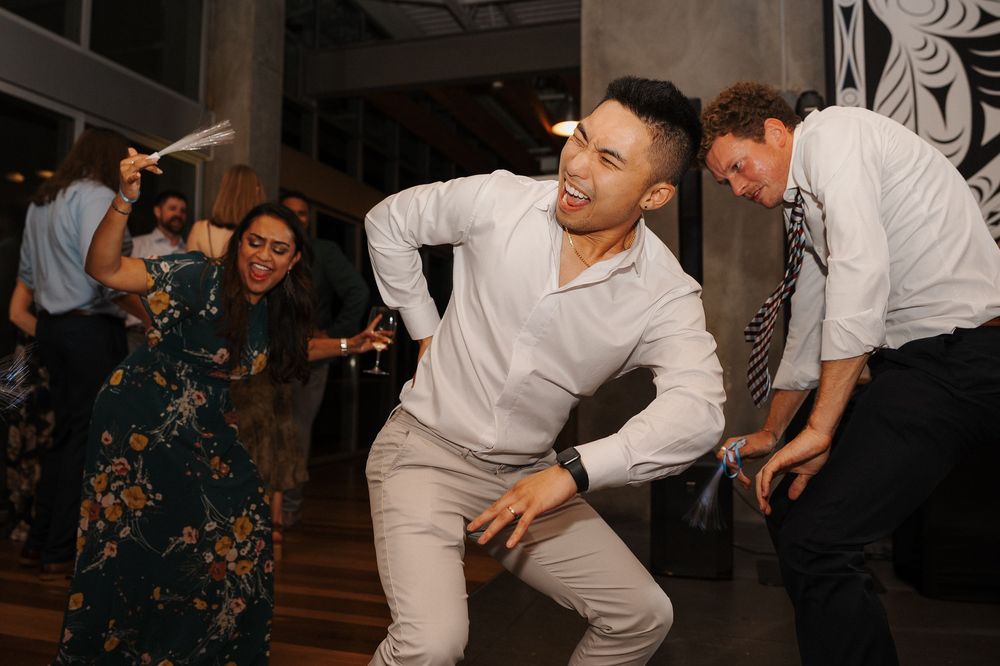 People in white outfits dancing energetically at a party with dark interior lighting and decorative elements.