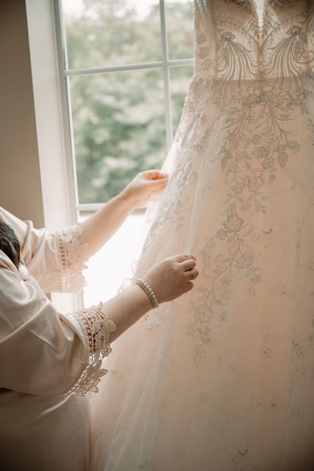 Bride adjusting dress before wedding ceremony in Dallas–Fort Worth in window