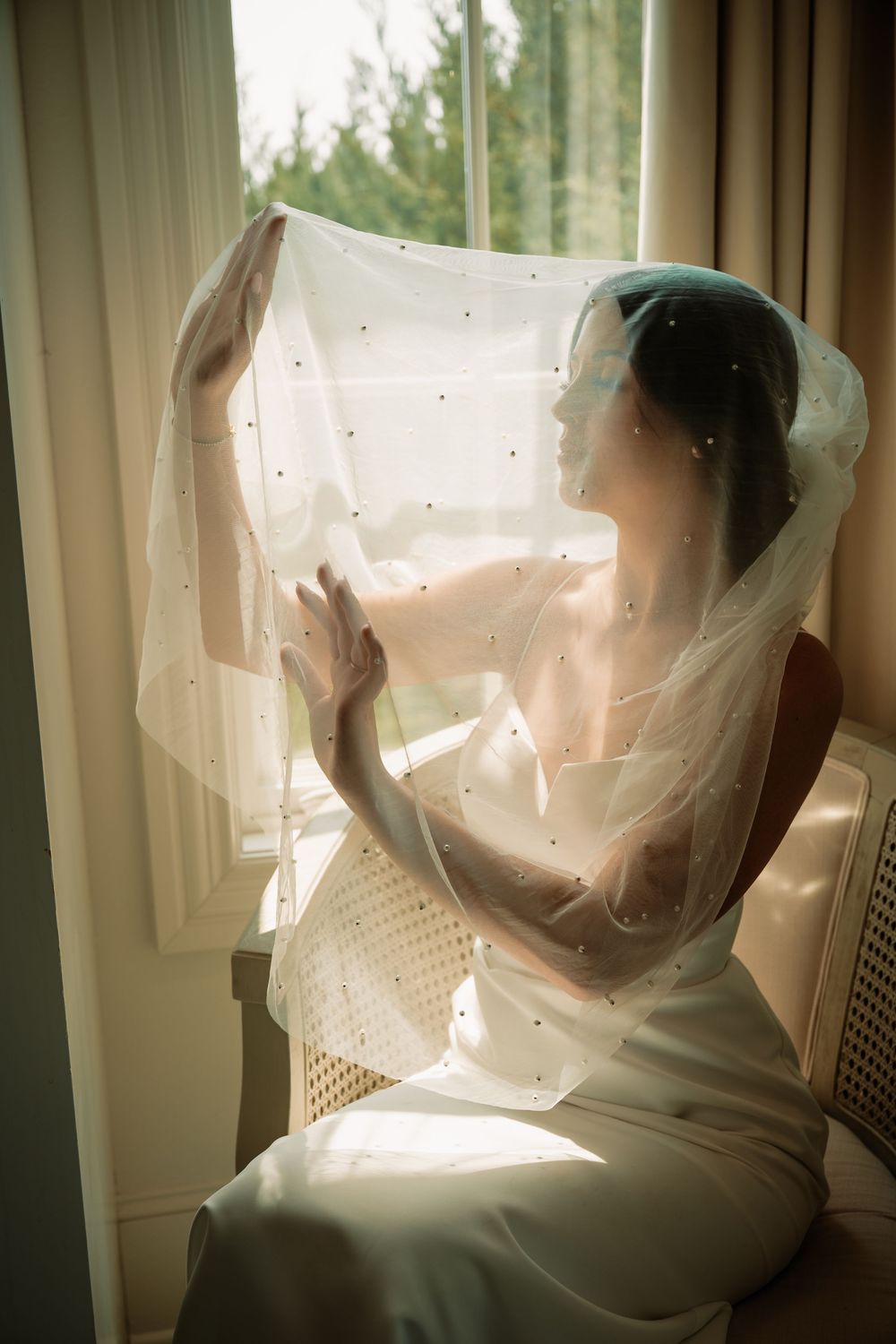 Bride sitting under veil by window at Hillside Estate wedding venue in Dallas–Fort Worth