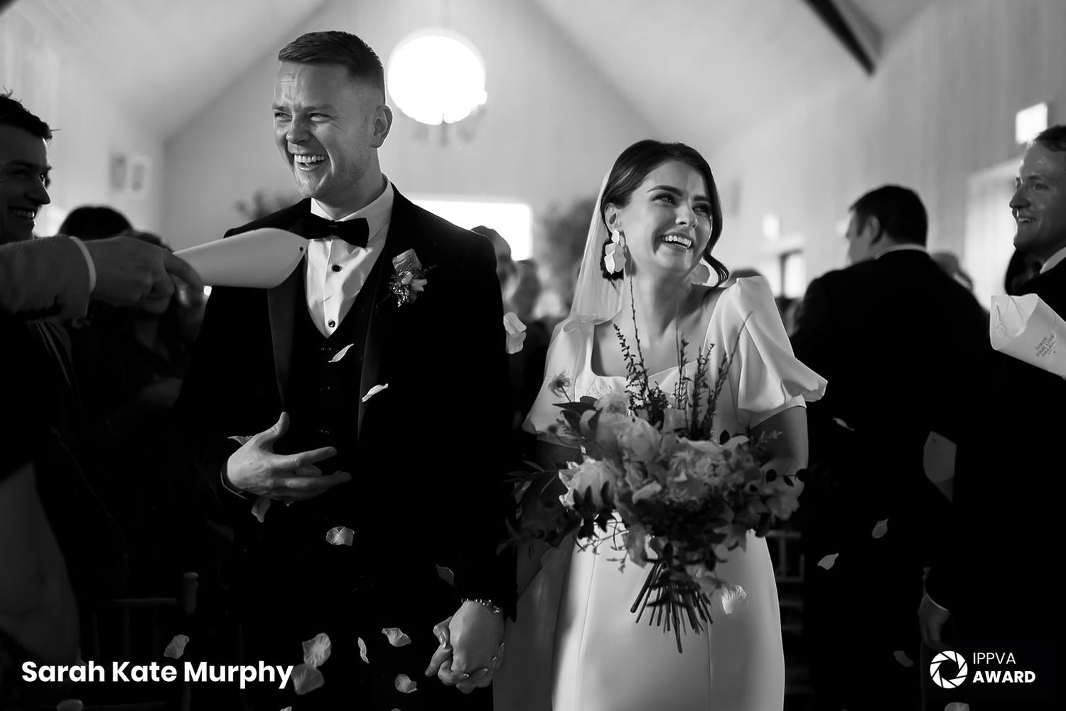 Black and white photo of newlyweds laughing joyfully during their wedding reception.