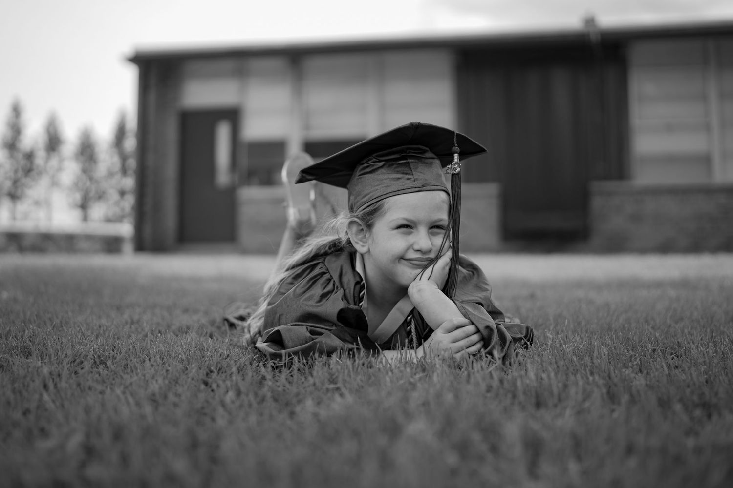 Graduate lying in grass looking up at the sky during graduation photoshoot.