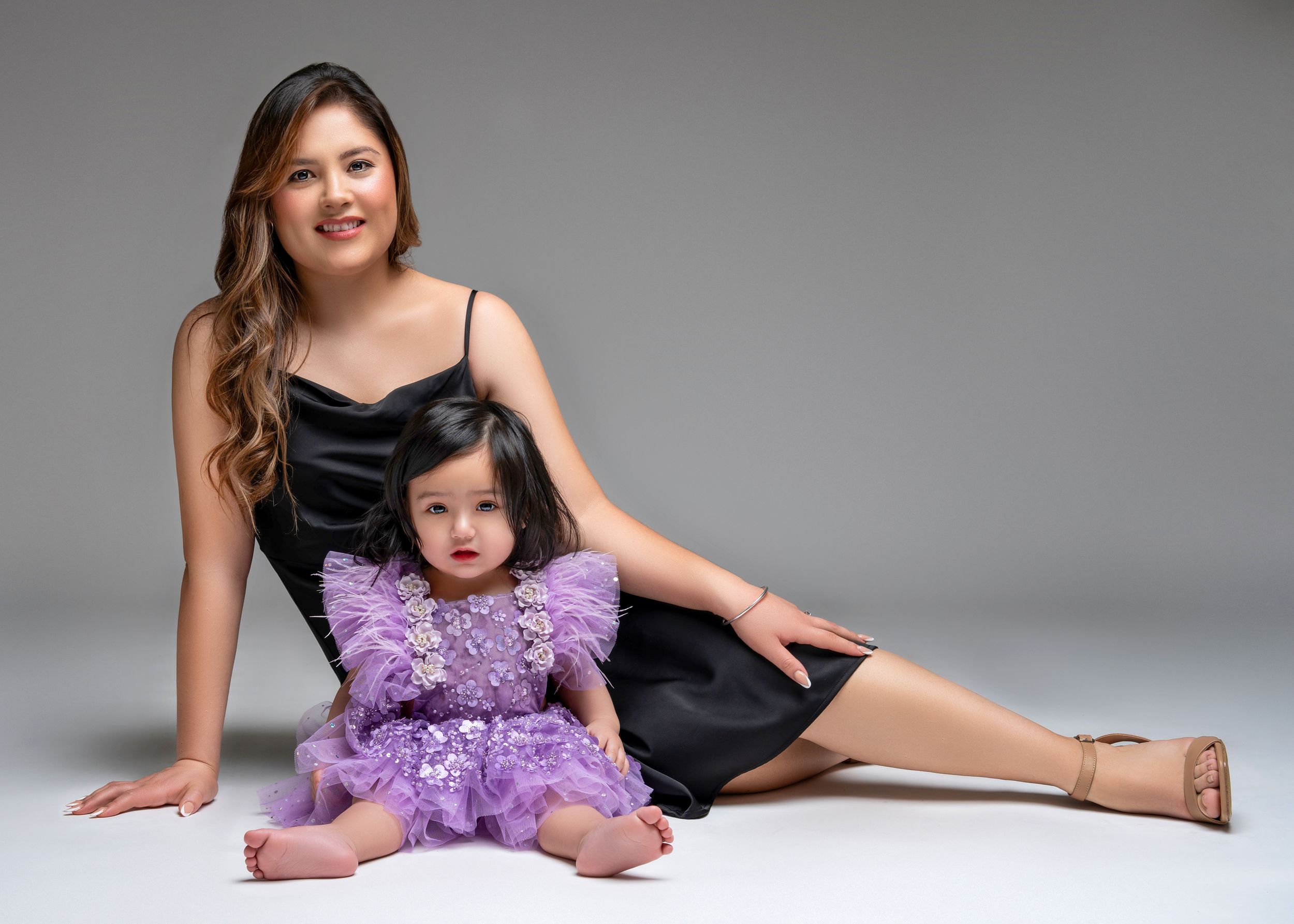 a woman lays behind her daughter in the studio with a motherhood photographer