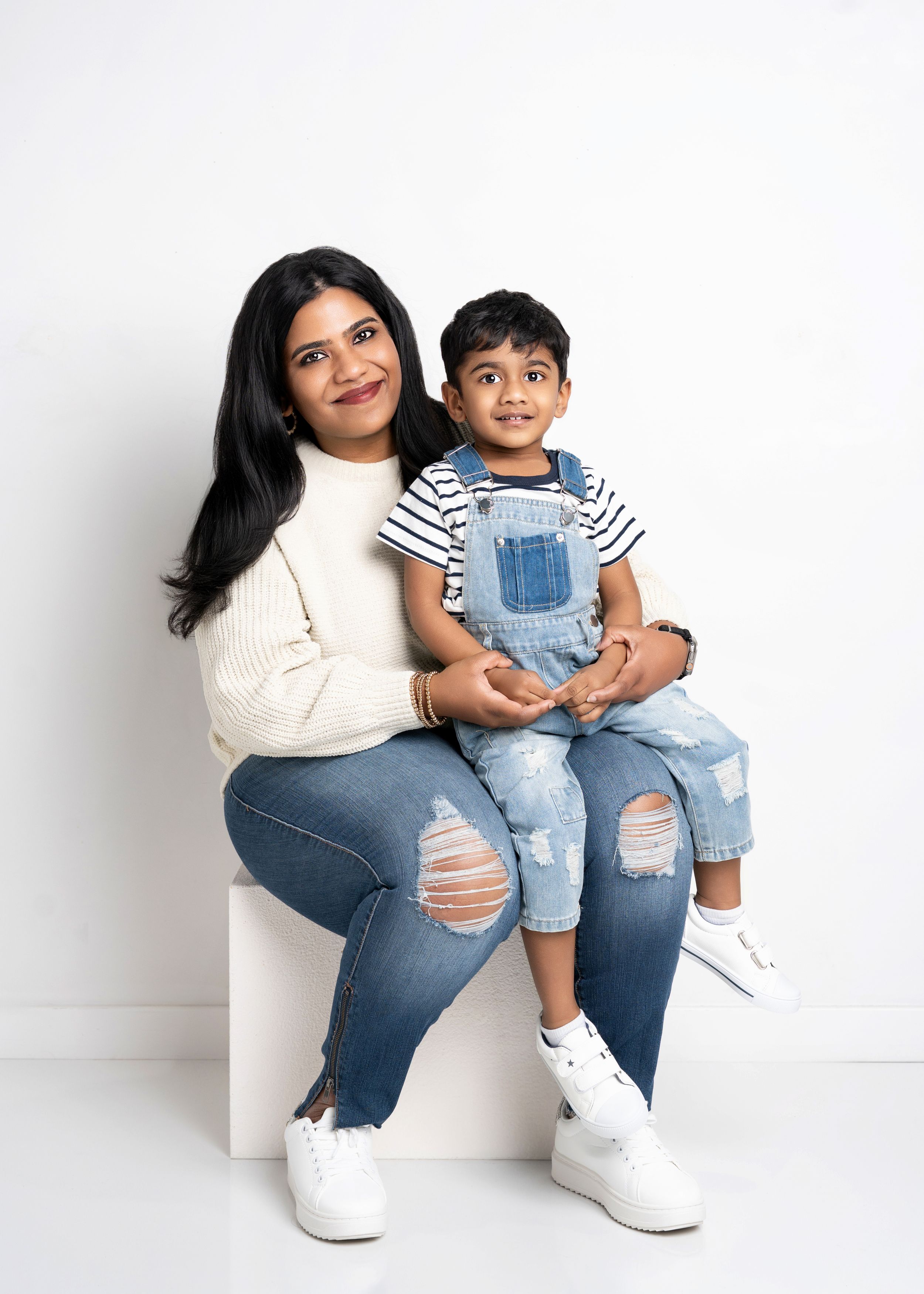 a mother sits with her son on a white cube with a motherhood photographer