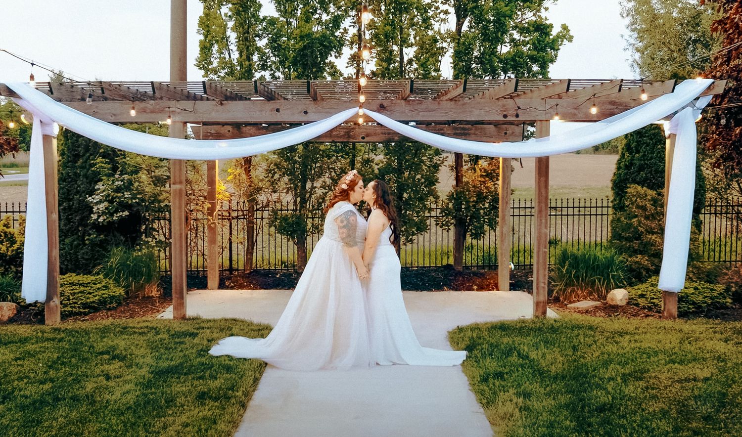 Newlyweds share intimate kiss under beautiful outdoor wedding arch.