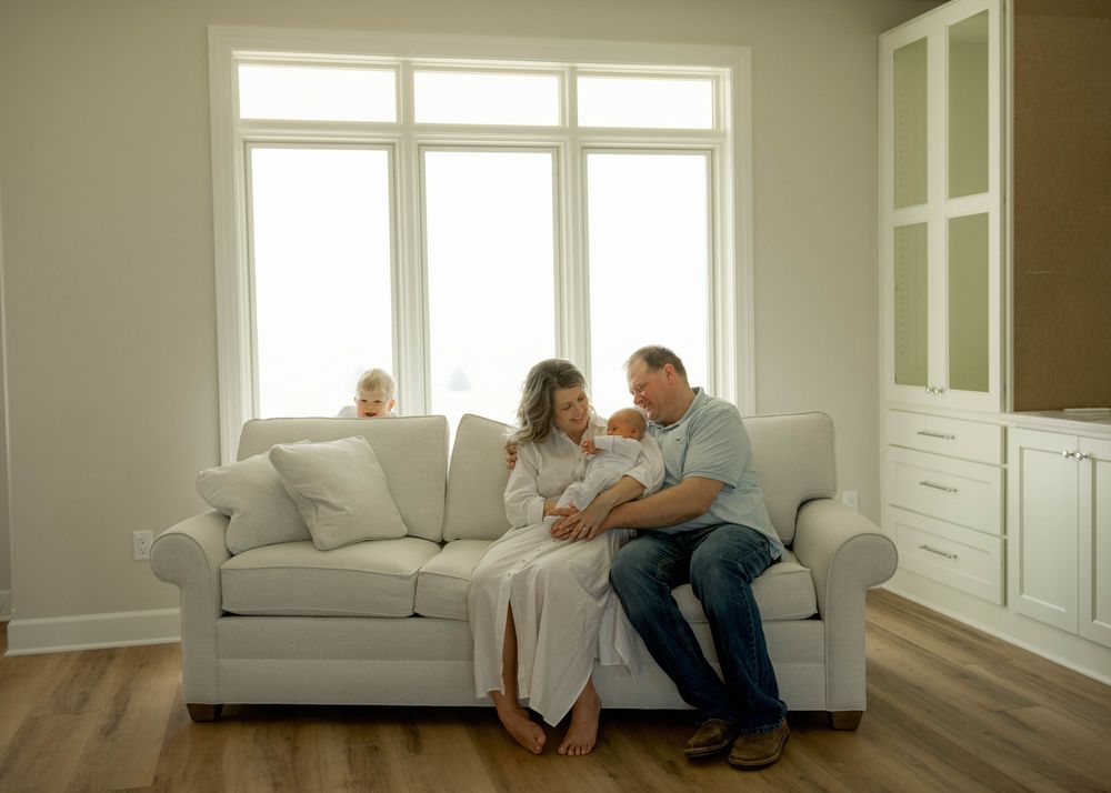 Minimalist family photography sequence in a bright room with large windows and neutral tones.