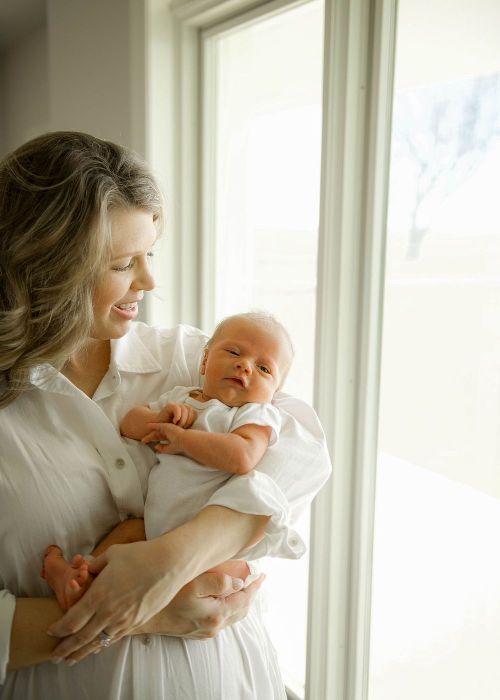 A tender moment captured in a series of intimate photos by a window with natural light streaming in.
