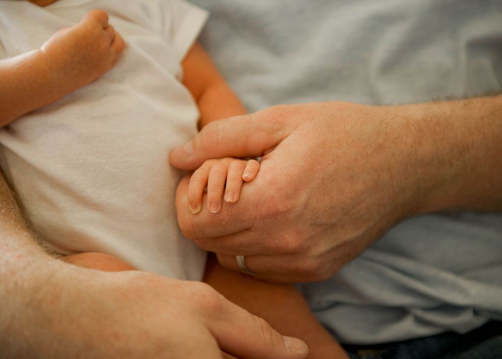 Close-up of gentle hands cradling a newborn baby in soft natural light.