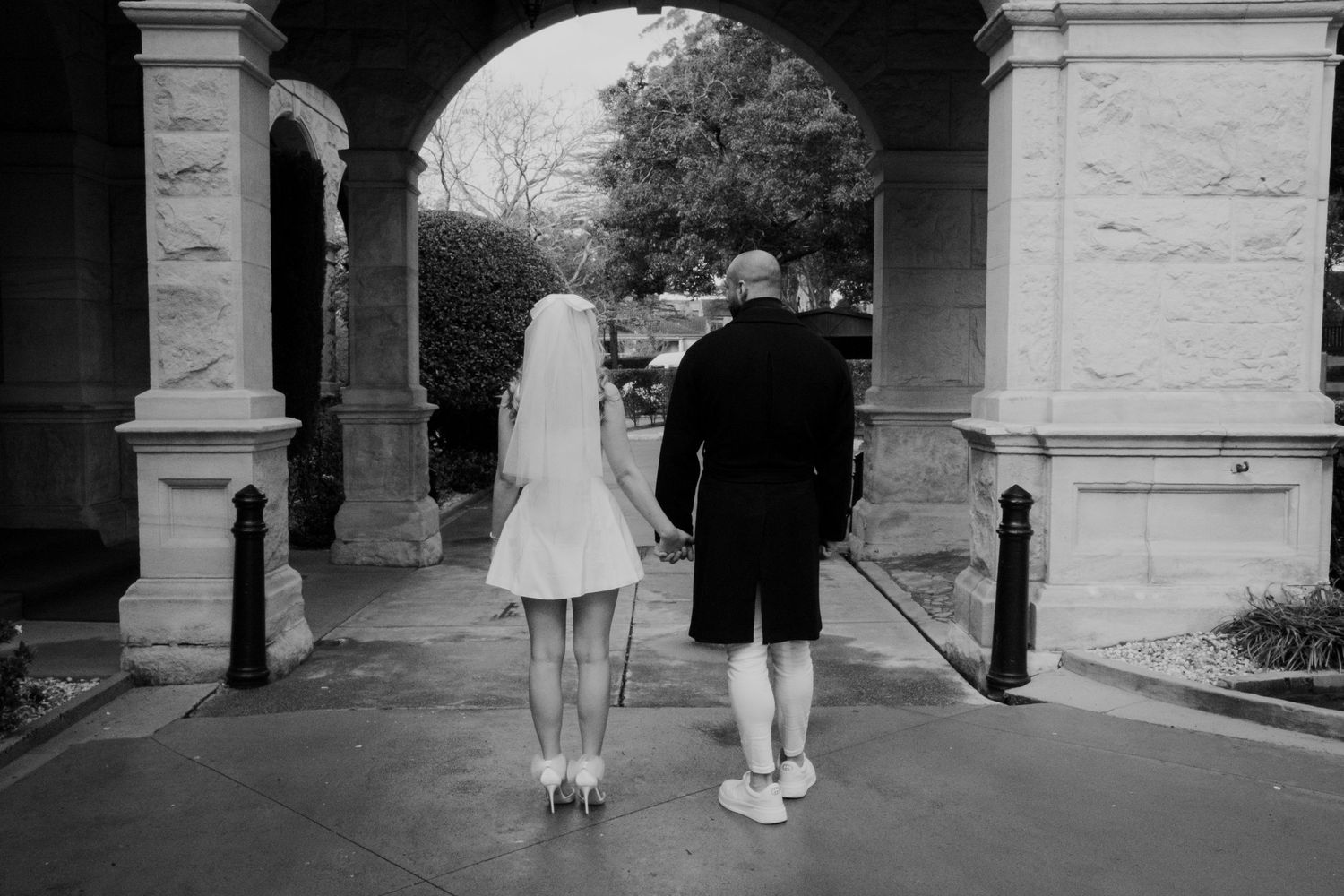 Black and white image of people walking through an architectural colonnade.