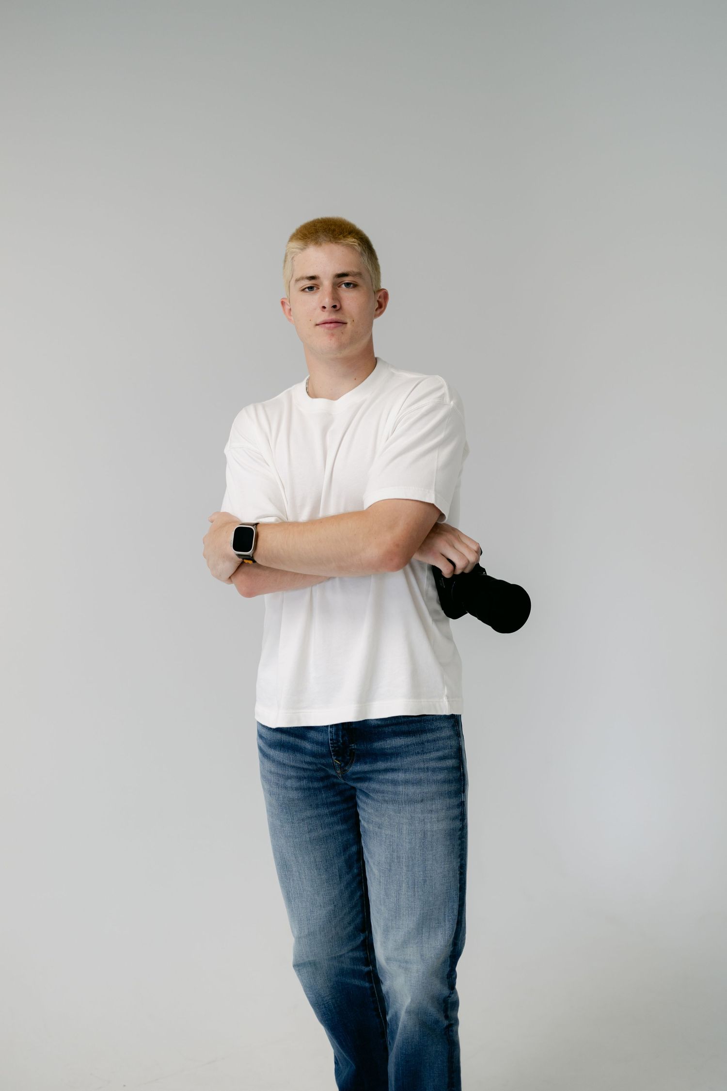 Studio portrait against grey background showing casual outfit with white t-shirt and jeans.