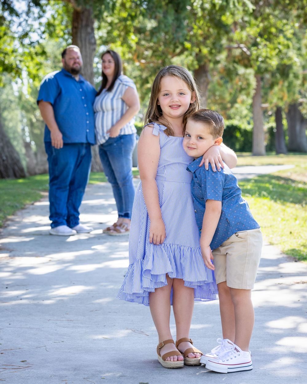 A family enjoying time together on a path surrounded by green trees on a sunny day.