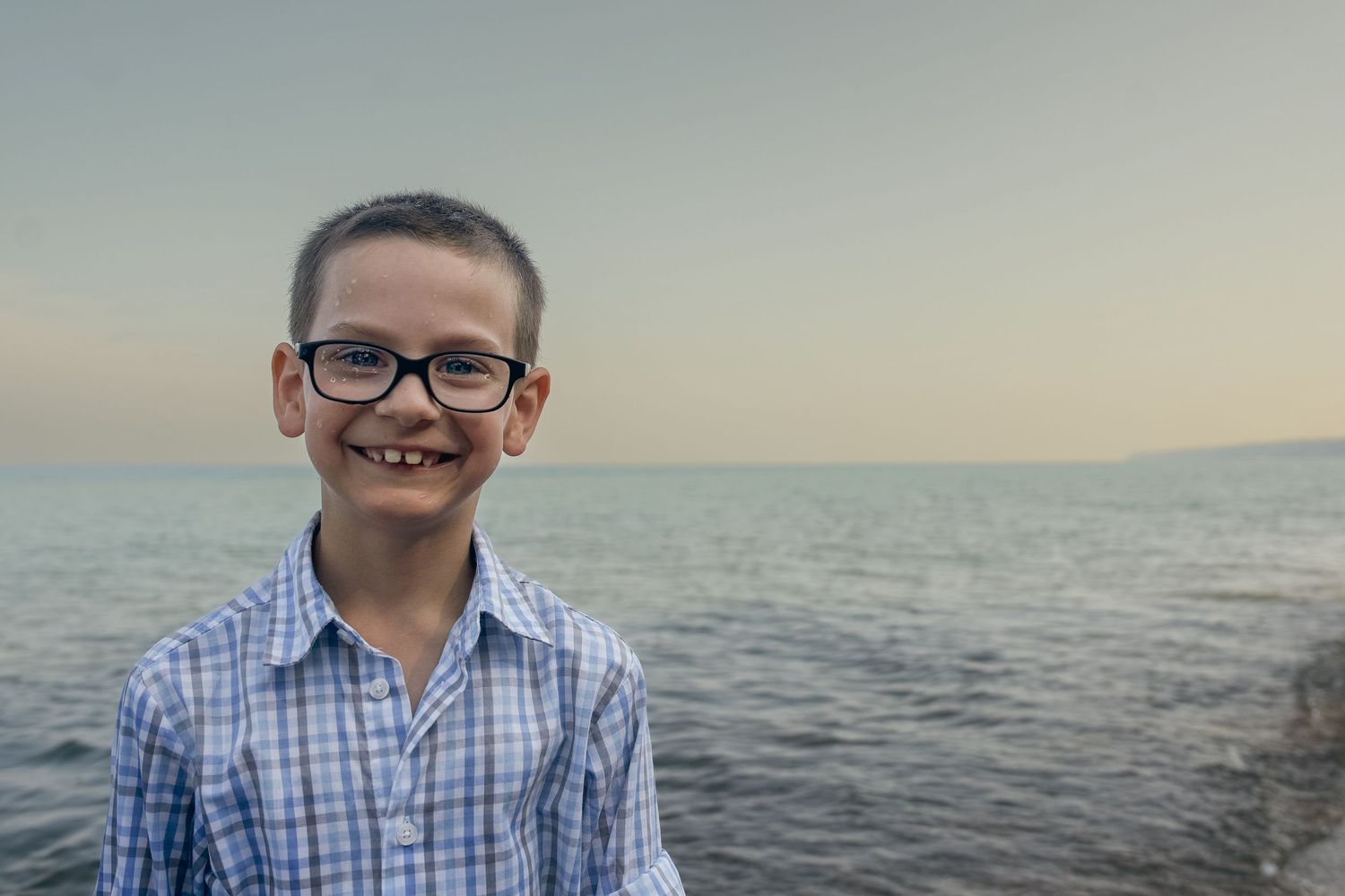 A collage of six photos showing someone in a blue checkered shirt posing near the ocean at sunset.