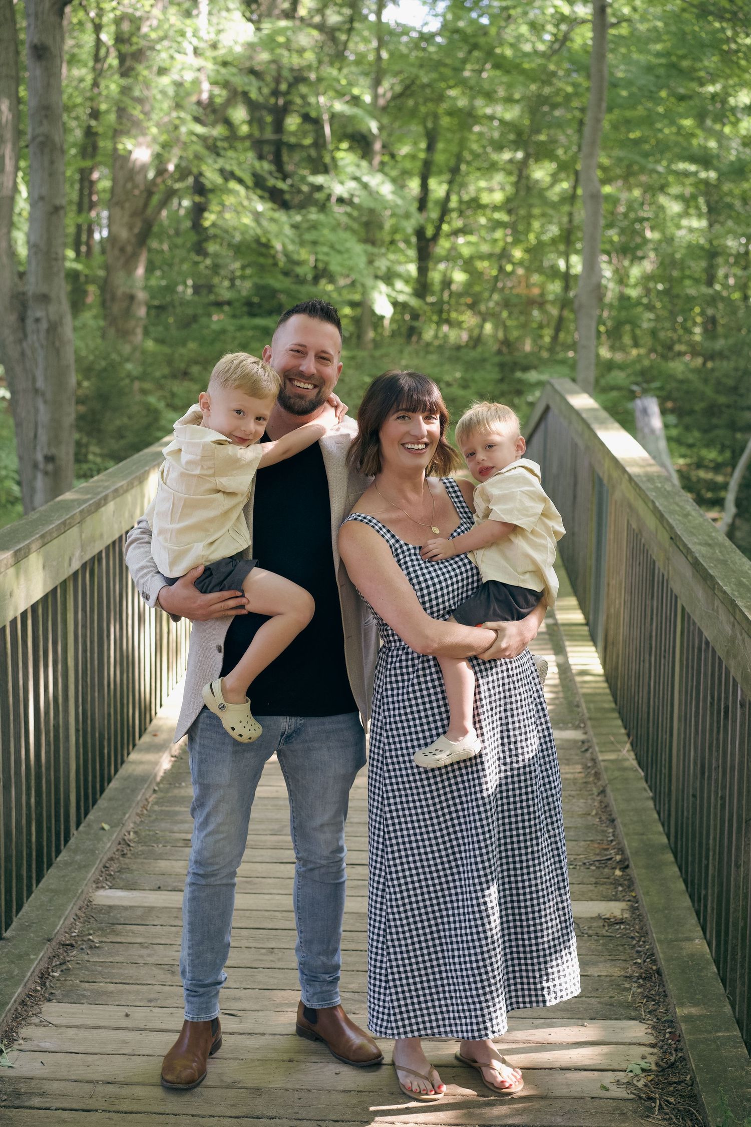 A happy family shares joyful moments together while posing on a wooden boardwalk in a lush forest setting.