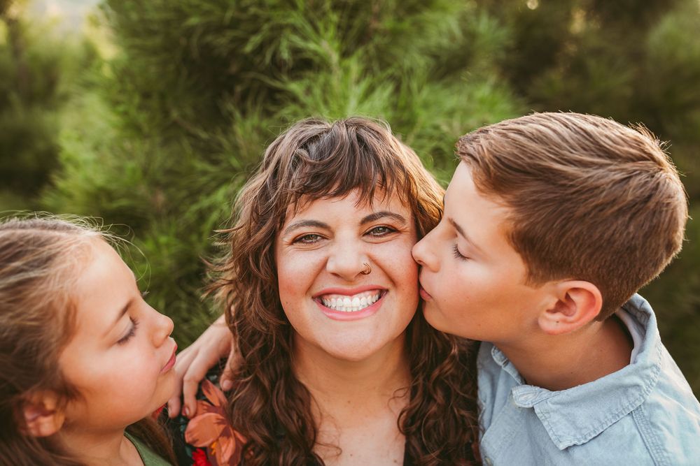 Three joyful people sharing playful moments together outdoors with greenery in the background.