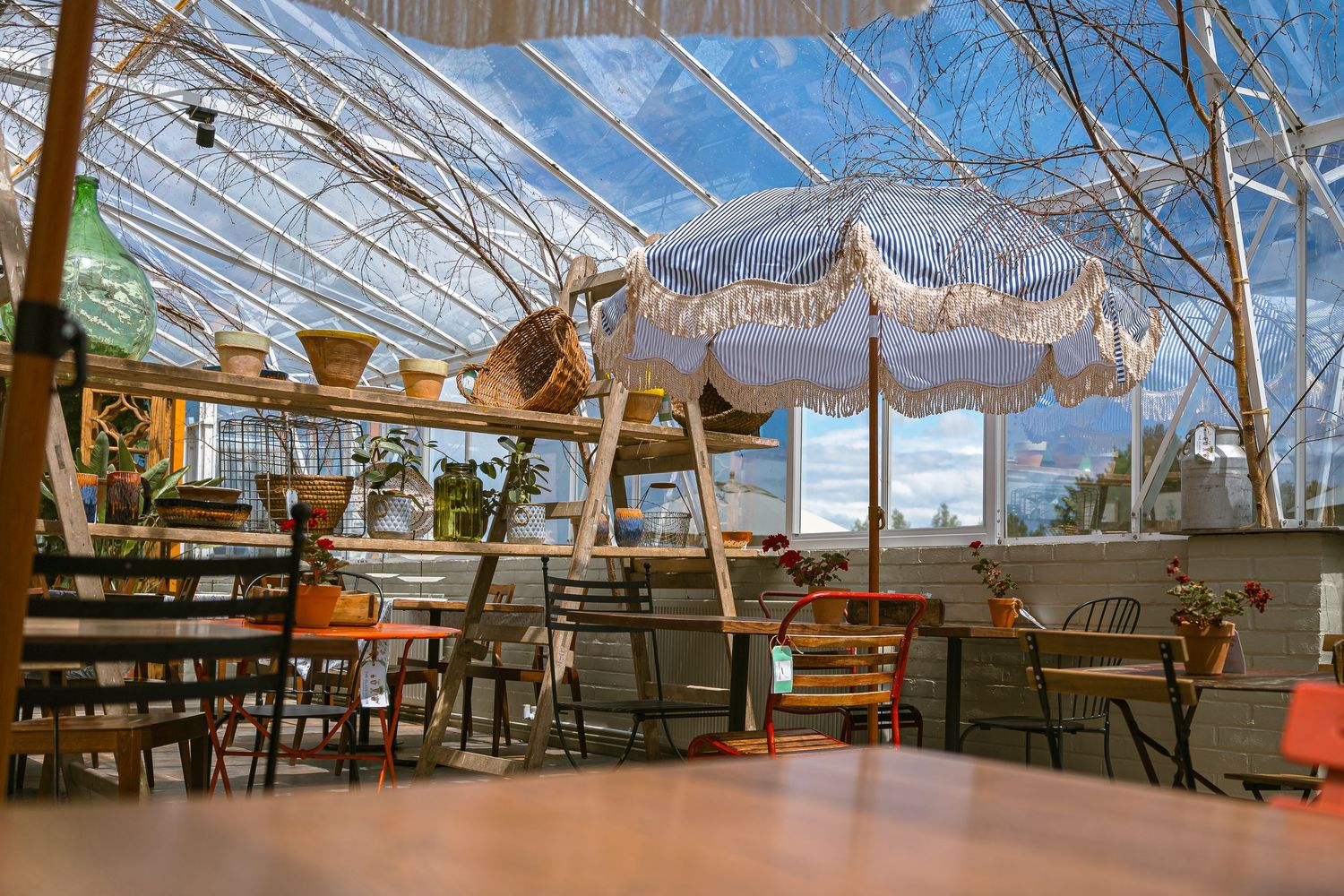 Large, sunlit conservatory restaurant interior with exposed wood beams, skylights and comfortable seating arrangements.