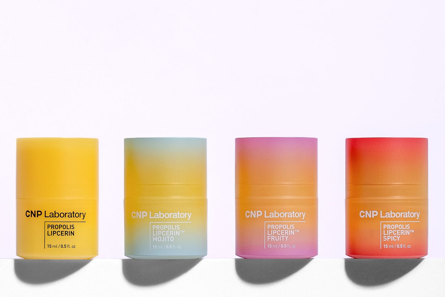 Four colorful DHM Laboratory skincare product containers in yellow, gold, pink and red casting shadows on white surface.