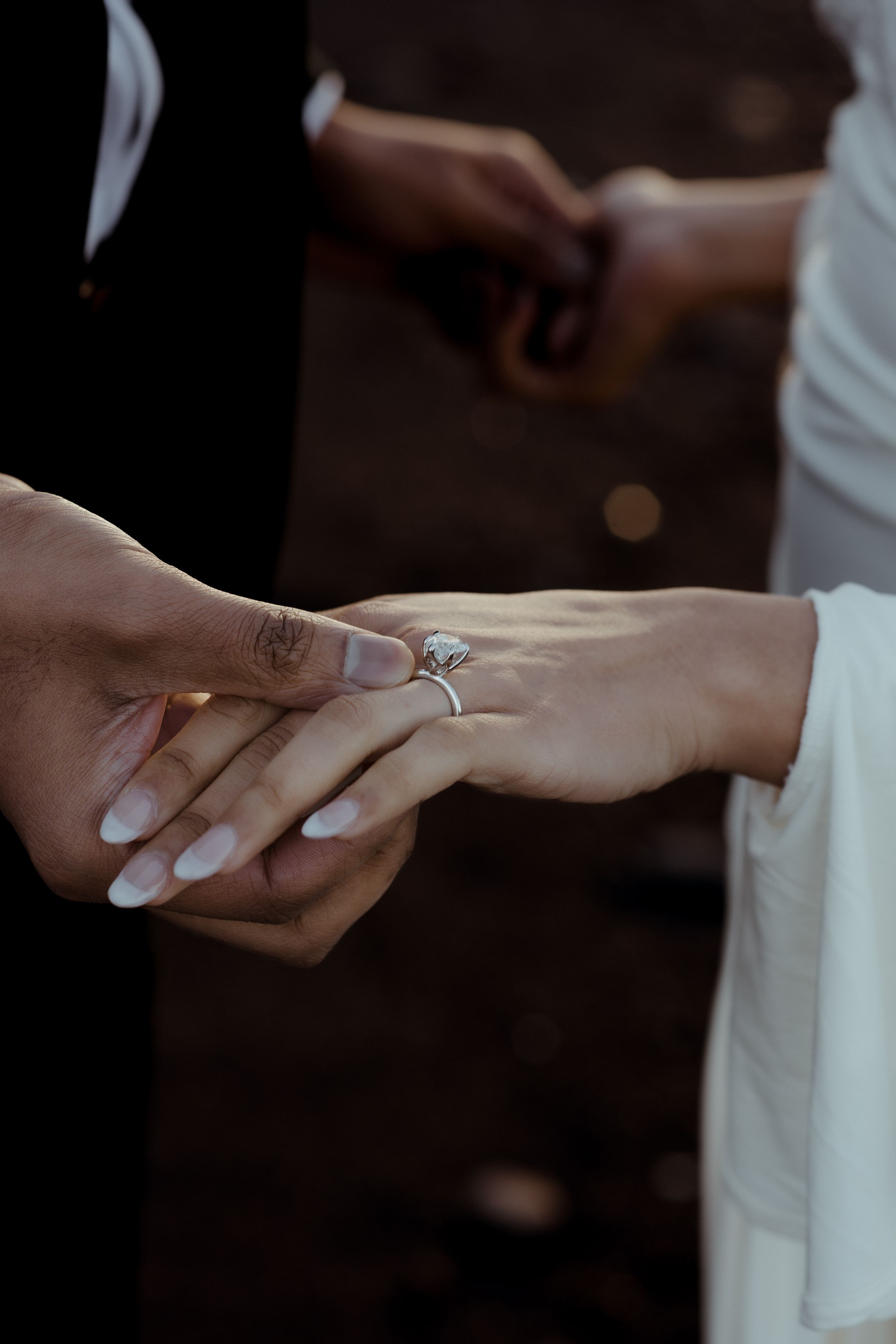 Close-up view of hands exchanging wedding rings during a romantic engagement or marriage ceremony.