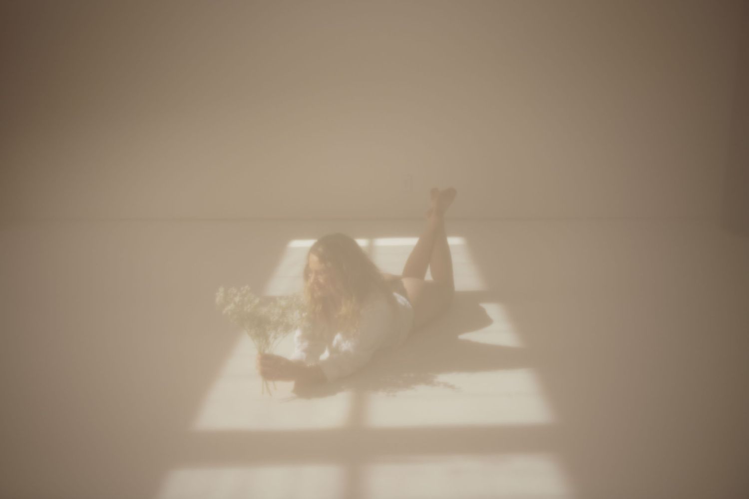 A dreamy, ethereal image shows a reclining silhouette bathed in soft window light casting geometric shadows.