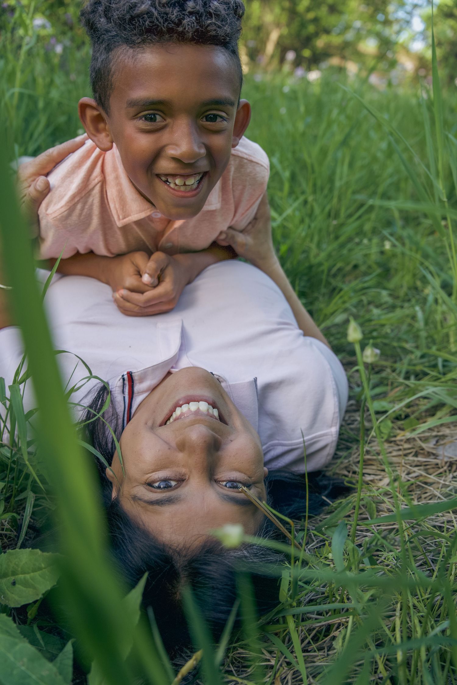 Two people lying on a beige blanket wearing white and olive green shirts while relaxing together.