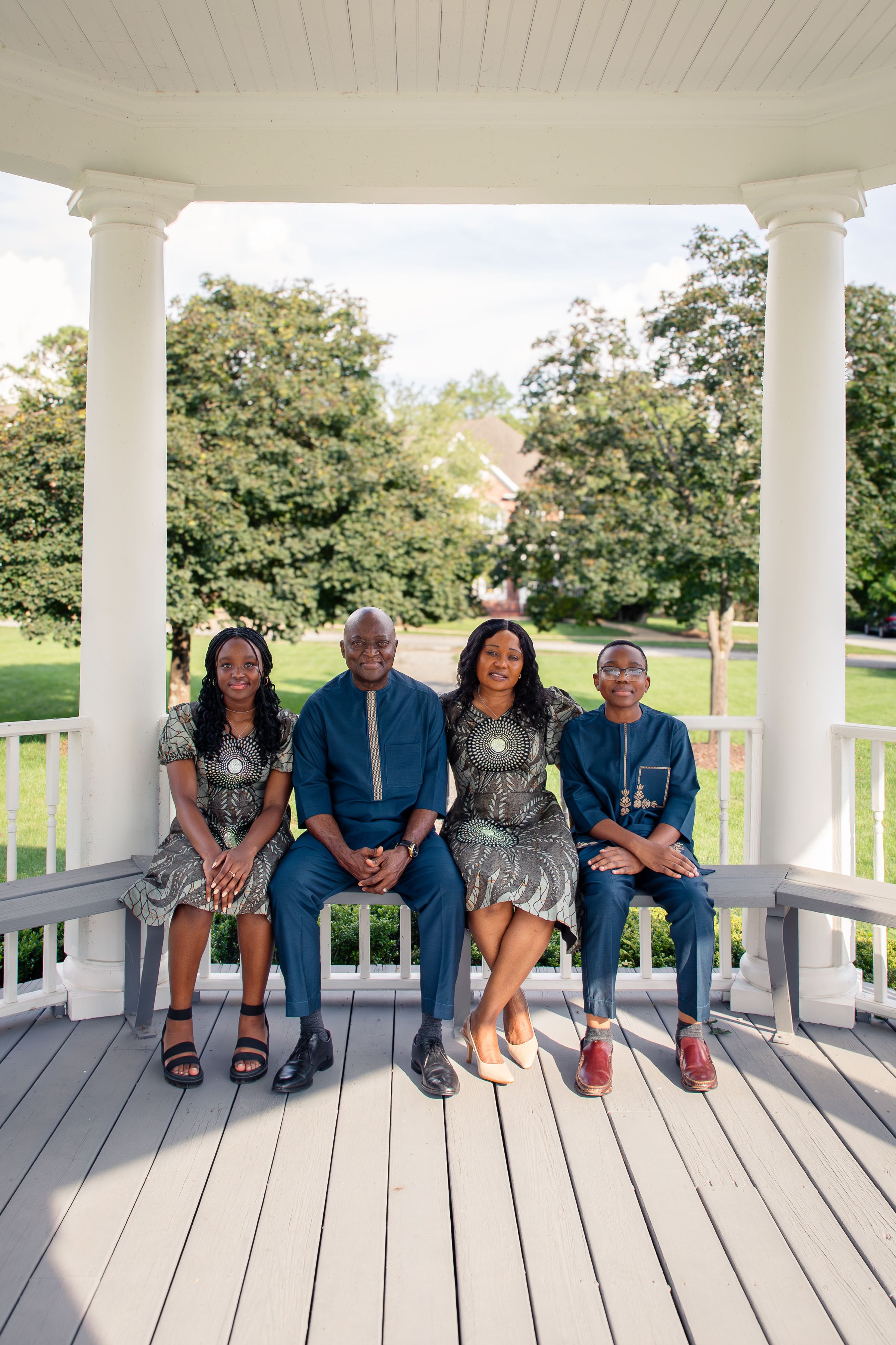 A group sits together on a white gazebo deck showing off their various footwear and shoes.