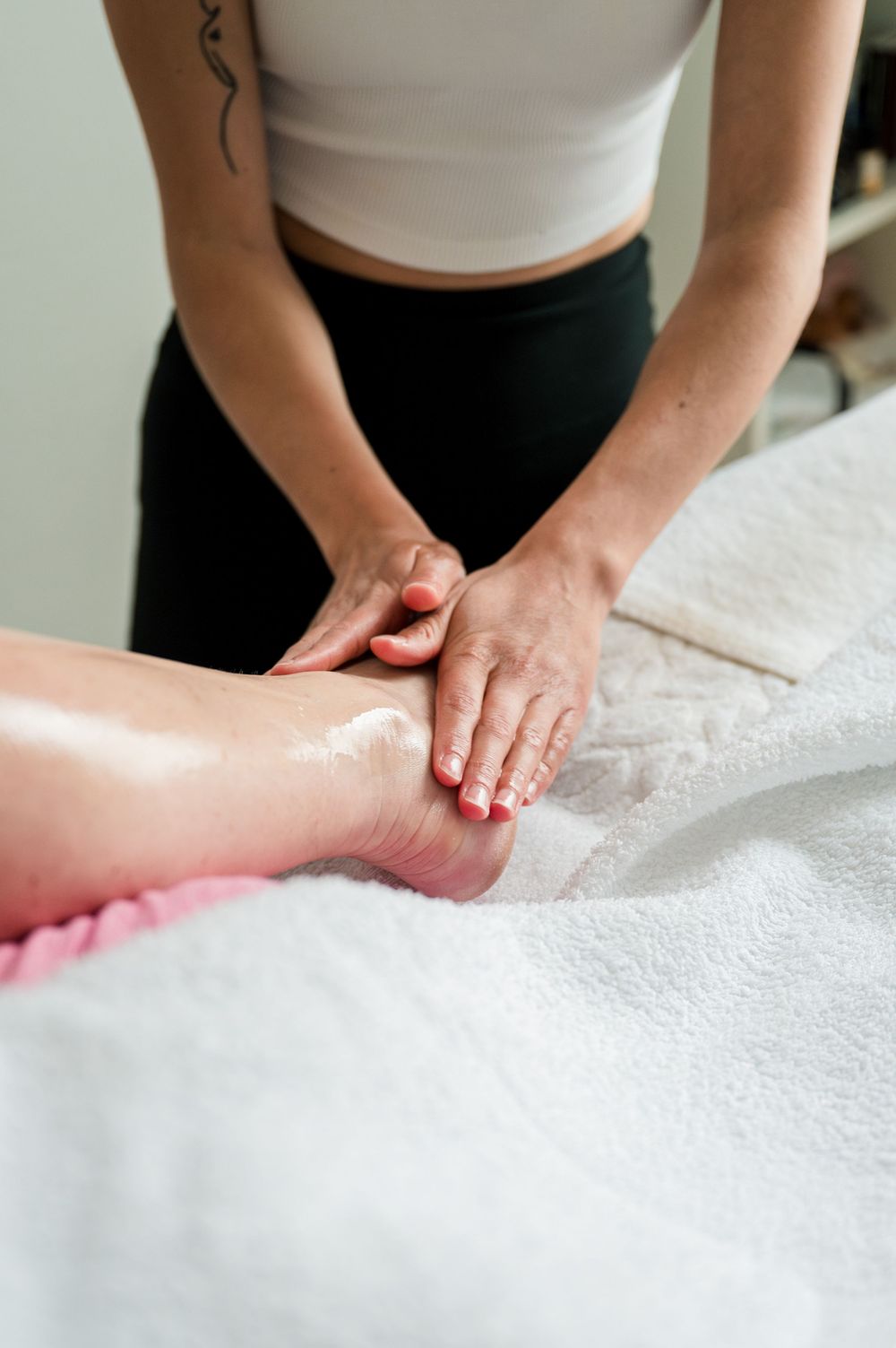 Hands demonstrating various massage techniques on a white massage table.
