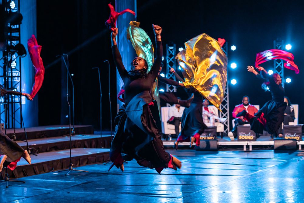 Dancers performing on a blue-lit stage with red decorative elements.