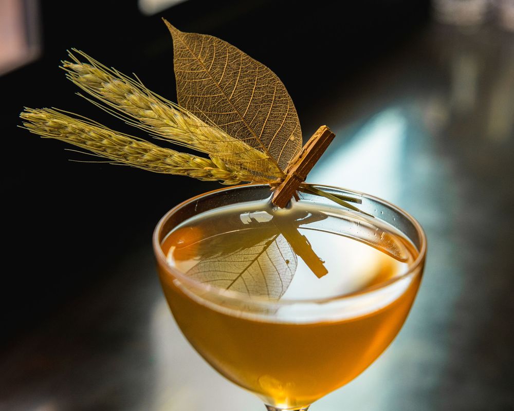 Elegant golden cocktail garnished with a decorative metallic dragonfly wing.