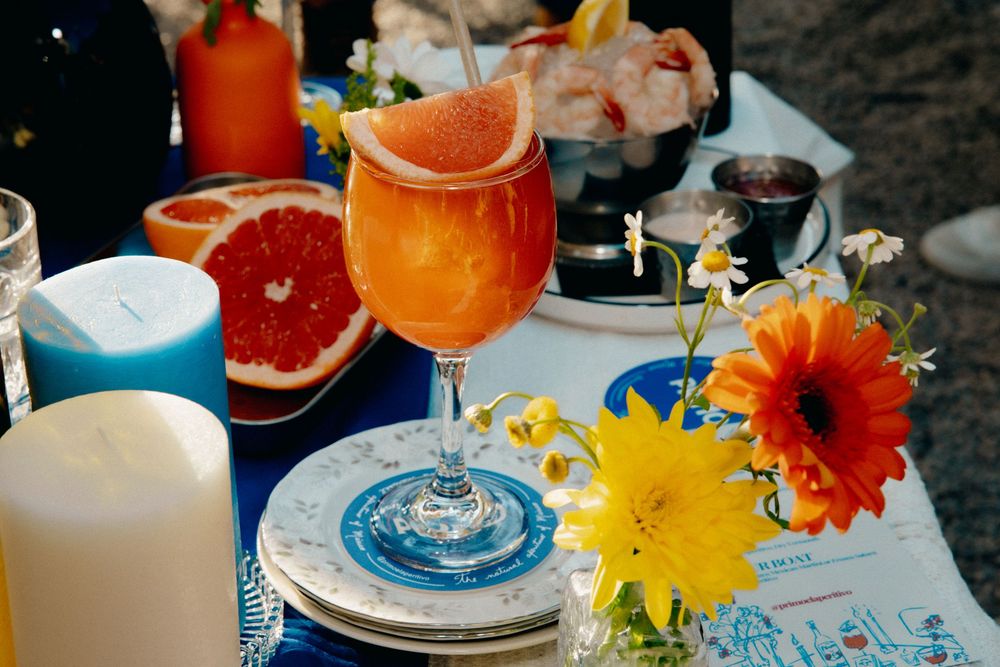 Colorful table setting with citrus fruits, flowers and place settings in vibrant blue and orange.