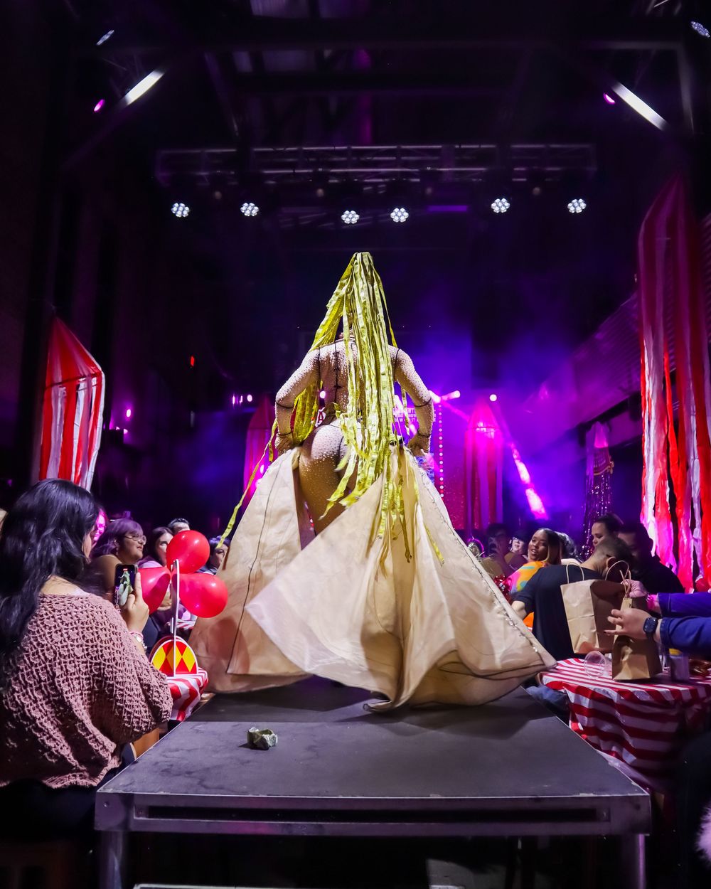 Dramatic stage performance with large illuminated fabric installations and purple lighting.