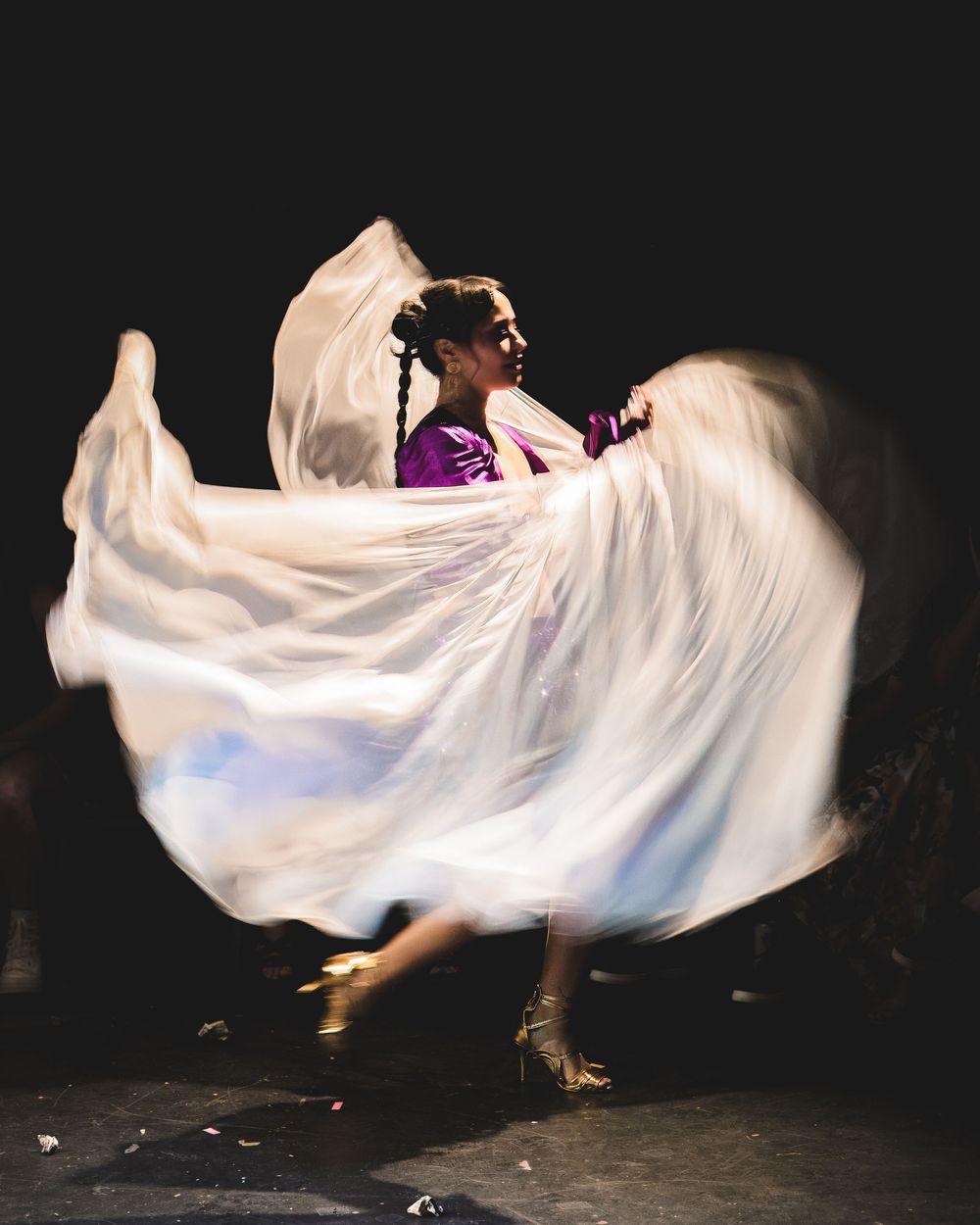 Artistic performance featuring flowing white fabric movement against a black background.