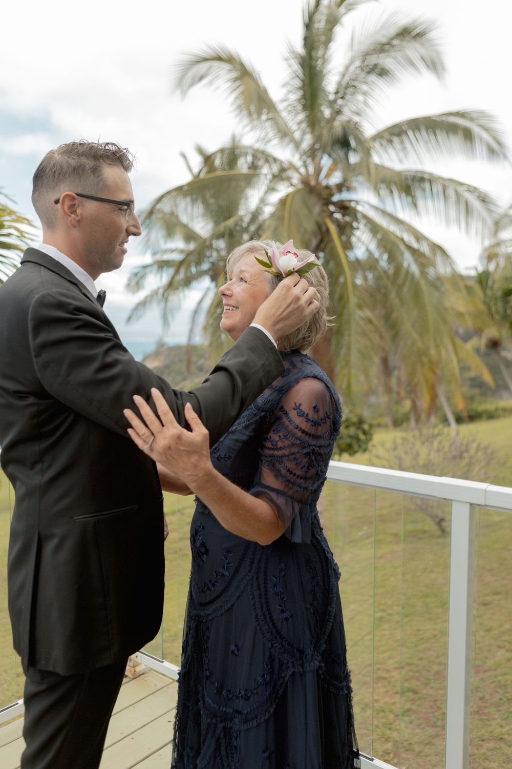 A couple dances together on a tropical deck with palm trees in the background.