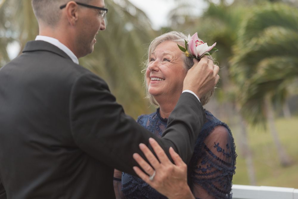 An emotional moment between someone in a navy dress and another person in a dark suit at an outdoor event with palm trees.