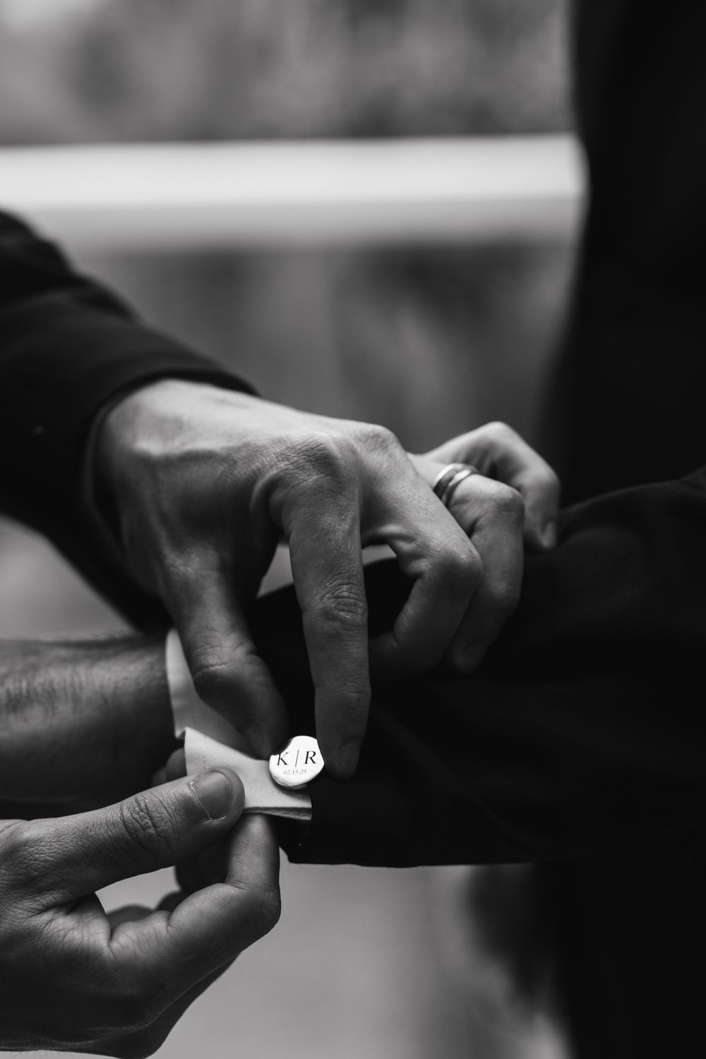 Close-up black and white shot of hands exchanging wedding rings during a ceremony.