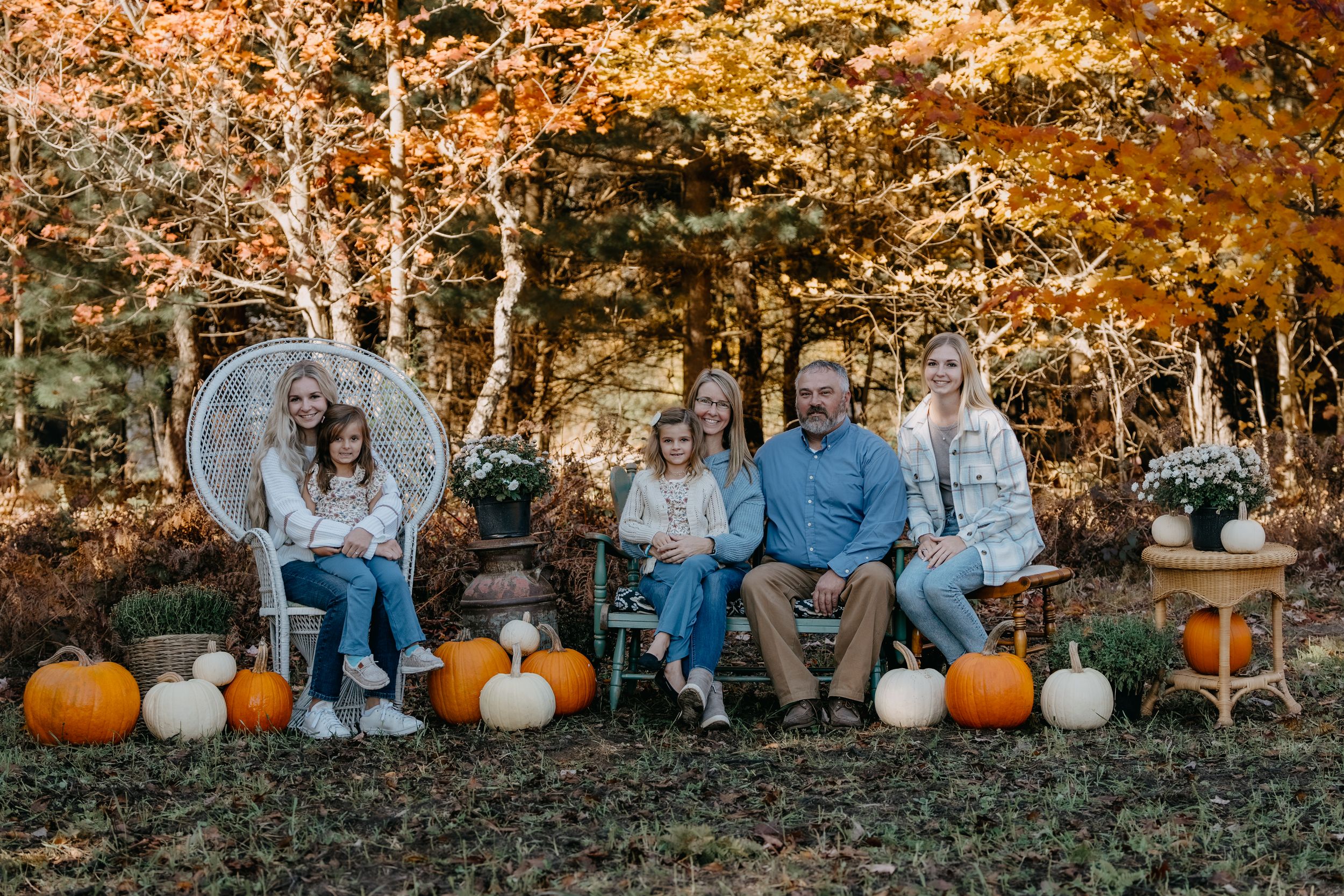Autumn outdoor display with figures seated among scattered pumpkins and fall foliage in warm golden lighting.